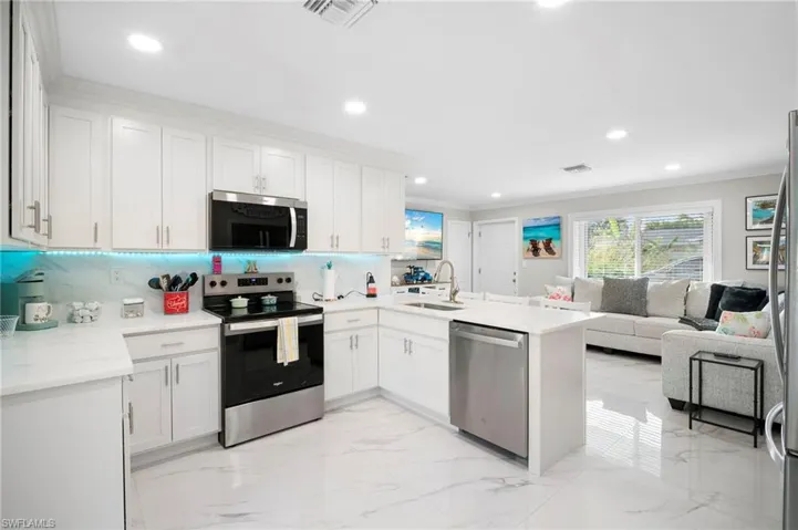 Kitchen with stainless steel appliances, a peninsula, crown molding, white cabinetry, and open floor plan
