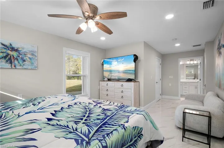 Bedroom with light marble finish flooring, recessed lighting, a ceiling fan, and ensuite bathroom