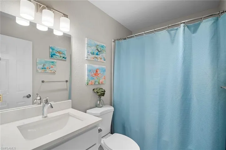 Full bathroom with a shower with curtain, vanity, and a textured wall
