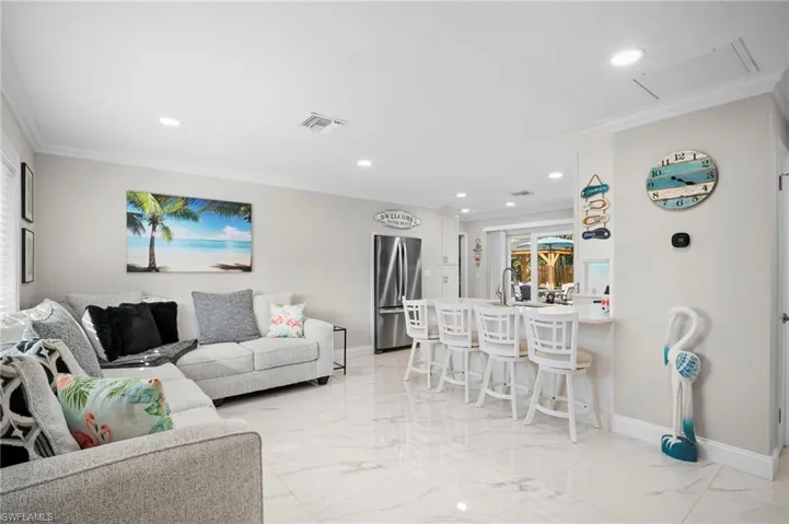 Living room featuring crown molding, light marble finish floors, and recessed lighting