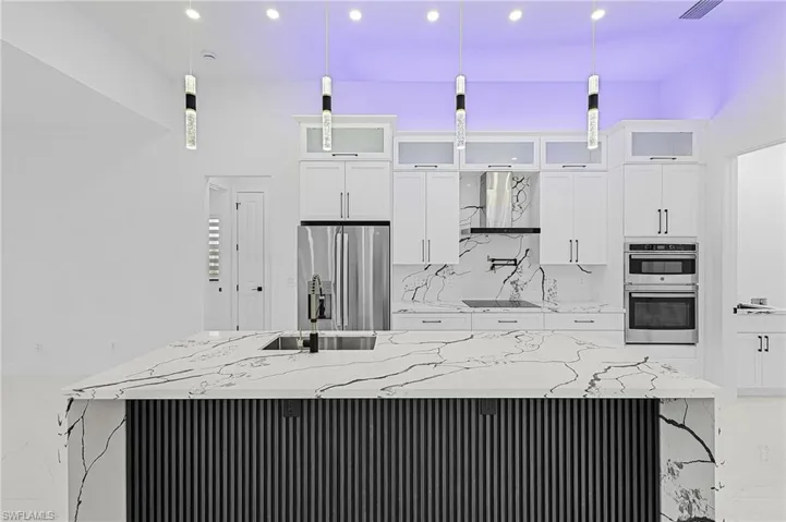 Kitchen featuring light stone counters, a sink, stainless steel appliances, white cabinetry, and marble finish floor
