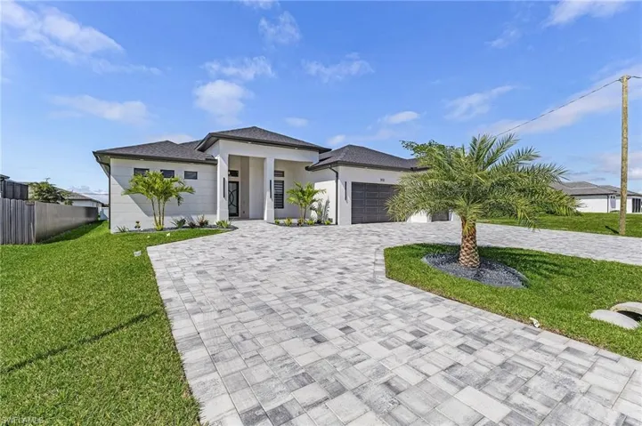 Prairie-style house featuring fence, a front yard, stucco siding, decorative driveway, and a garage