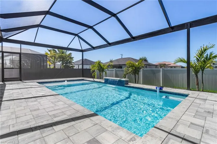 View of pool featuring a waterfall and sun deck with screen enclosure.