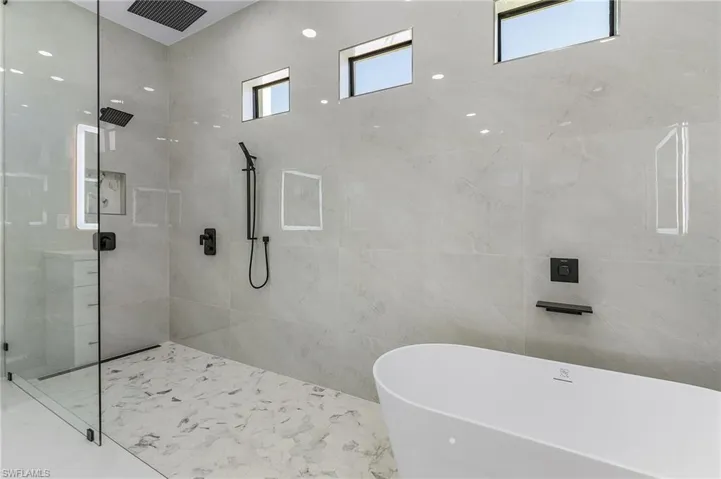 Full bathroom with a tile shower, marble finish floor, tile walls, and a freestanding tub