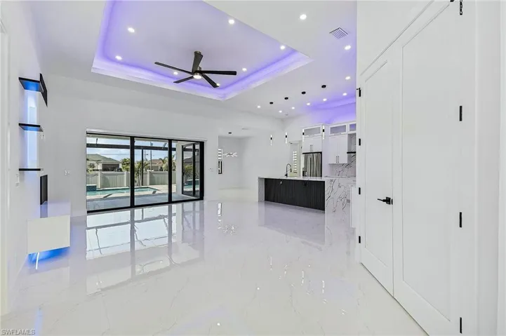 Unfurnished living room with a tray ceiling, visible vents, marble finish floor, and a sink