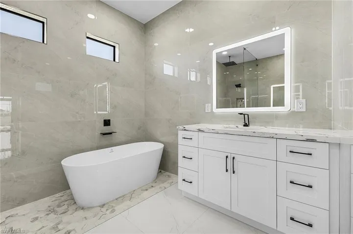 Bathroom featuring vanity, a shower stall, marble finish floor, and a freestanding bath