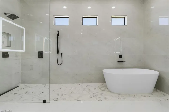 Full bath featuring a soaking tub, marble finish floor, and a walk in shower