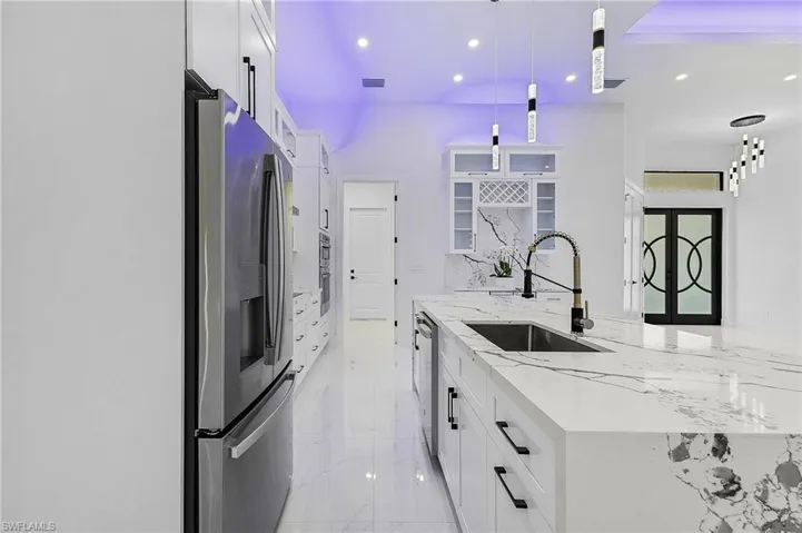 Kitchen with marble finish floor, a sink, stainless steel appliances, white cabinets, and glass insert cabinets