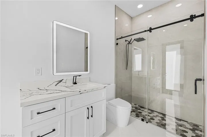 Full bathroom featuring marble finish floor, vanity, a shower stall, and toilet