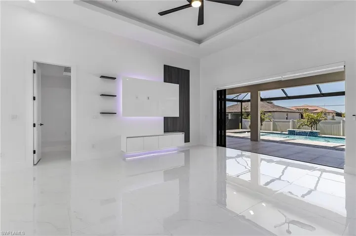 Empty room featuring marble finish floor, a ceiling fan, a tray ceiling, baseboards, and a towering ceiling