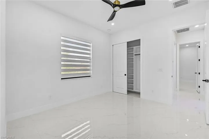 Unfurnished bedroom with a closet, visible vents, porcelain floor, and fan