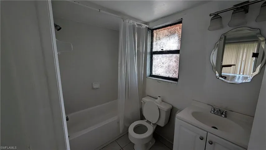 Full bathroom featuring shower / bath combo with shower curtain, vanity, and light tile patterned flooring