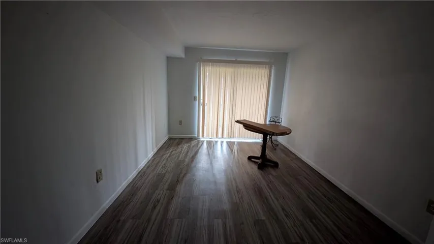 Empty room featuring baseboards and dark wood-style floors
