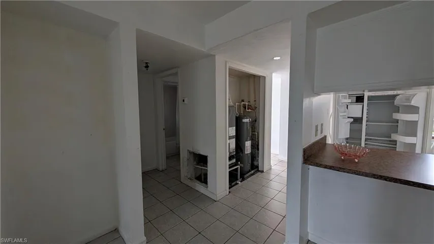 Kitchen with light tile patterned floors and water heater