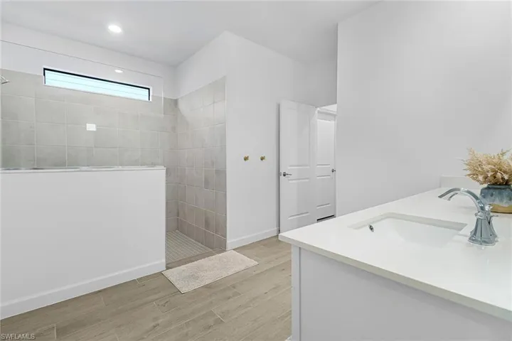Bathroom featuring a tile shower, wood-type flooring, and vanity