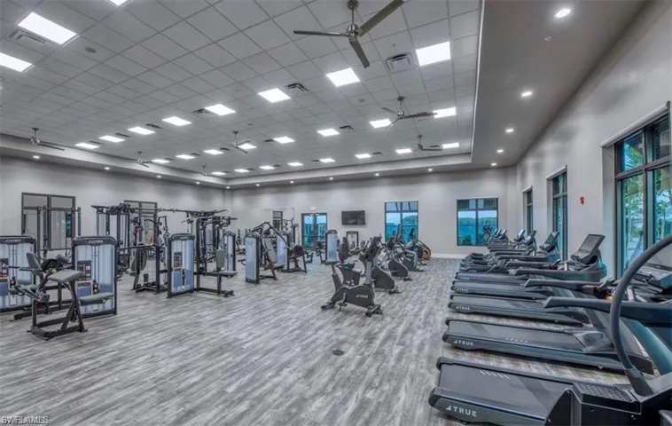 Workout area featuring a towering ceiling, ceiling fan, and a drop ceiling