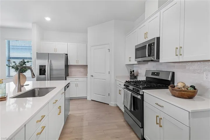 Kitchen featuring white cabinets, backsplash, light hardwood / wood-style flooring, and stainless steel appliances