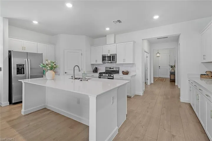 Kitchen featuring stainless steel appliances, sink, an island with sink, and white cabinets