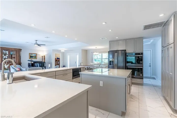 Kitchen with sink, gray cabinetry, stainless steel appliances, ceiling fan, and a spacious island