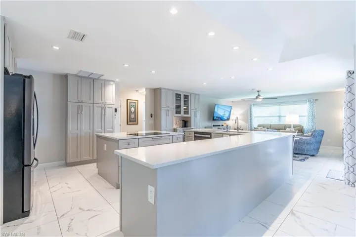 Kitchen featuring appliances with stainless steel finishes, gray cabinetry, kitchen peninsula, ceiling fan, and a spacious island