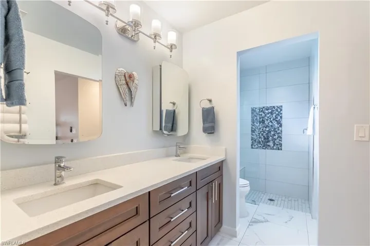 Bathroom featuring tiled shower, vanity, and toilet