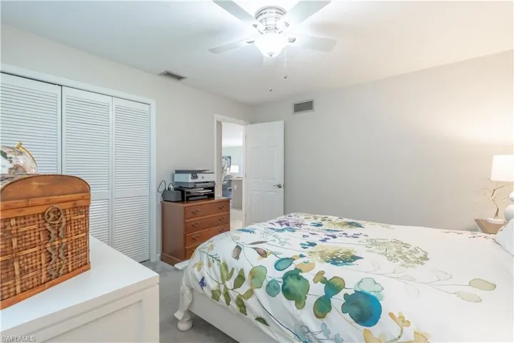 Bedroom with ceiling fan, light colored carpet, and a closet