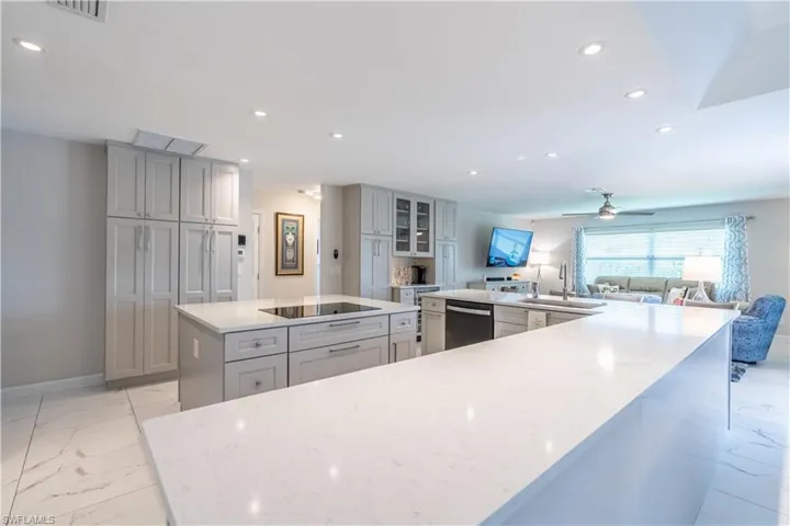 Kitchen with a large island, sink, black electric cooktop, ceiling fan, and stainless steel dishwasher