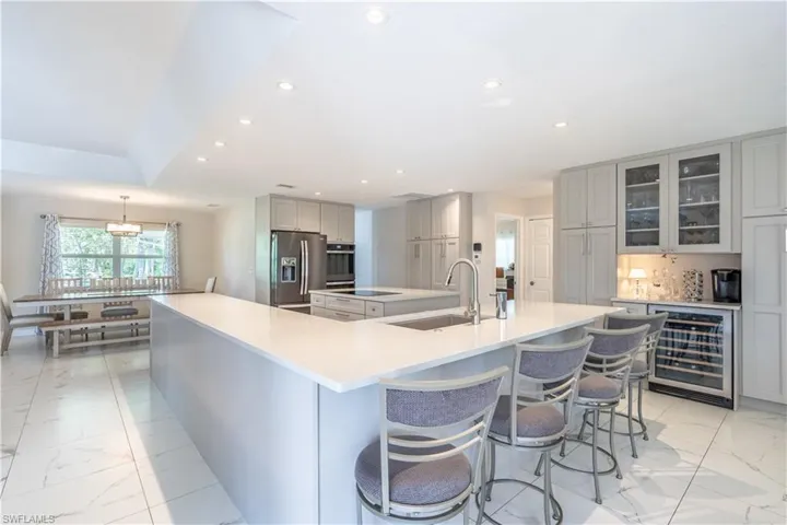 Kitchen with appliances with stainless steel finishes, gray cabinetry, wine cooler, a large island, and sink