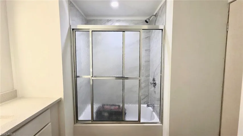 Bathroom with bath / shower combo with glass door and vanity