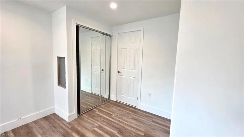 Unfurnished bedroom with wood finished floors and a closet
