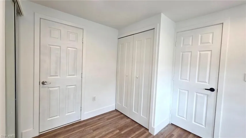 Unfurnished bedroom with dark wood-style flooring and a closet