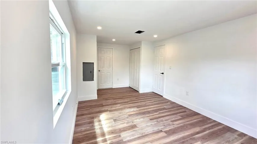 Unfurnished room featuring light wood-style flooring, electric panel, and recessed lighting