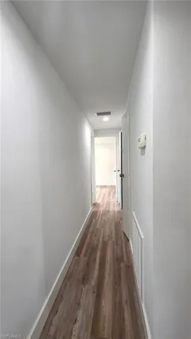 Hall featuring dark wood-style flooring and baseboards