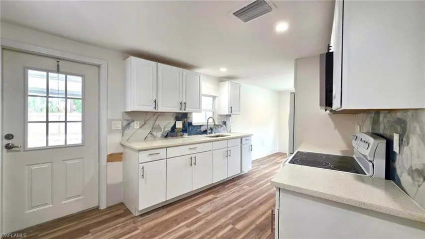Kitchen with white cabinetry, white range with electric cooktop, light wood finished floors, decorative backsplash, and recessed lighting