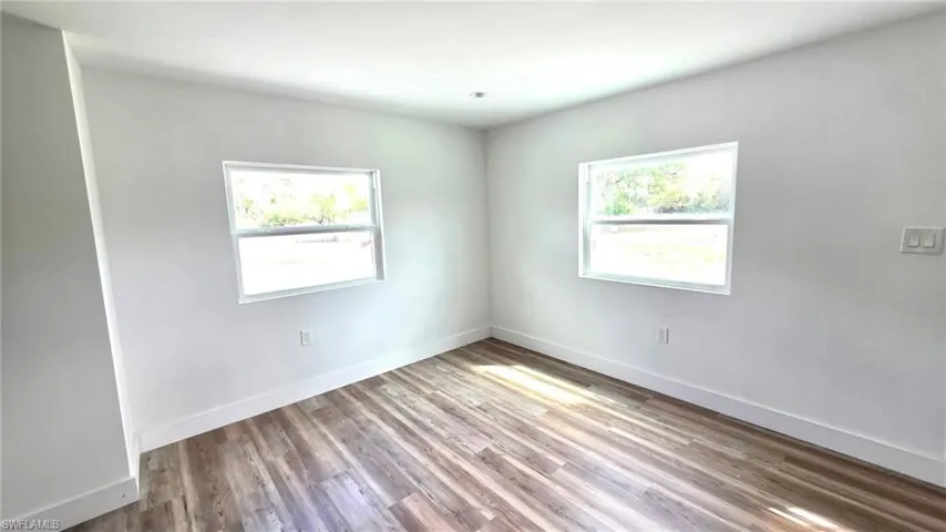 Spare room featuring light wood-style flooring and baseboards