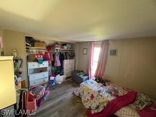 Bedroom featuring a textured ceiling, wood finished floors, and a closet