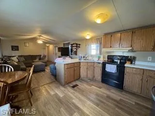 Kitchen with a peninsula, light countertops, black / electric stove, light wood-style floors, and open floor plan