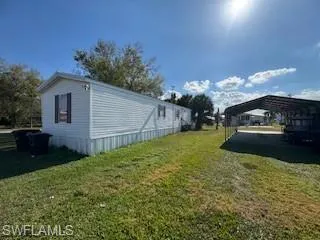 View of property exterior with a yard and a detached carport