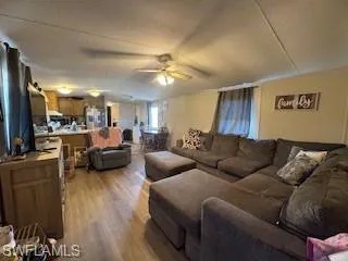 Living room featuring wood finished floors, a textured ceiling, ceiling fan, and lofted ceiling