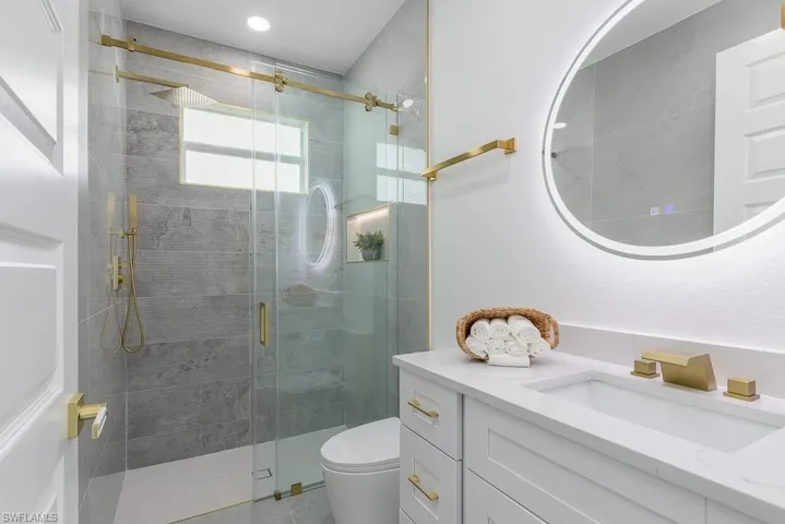 Bathroom with a shower with shower door, toilet, and vanity