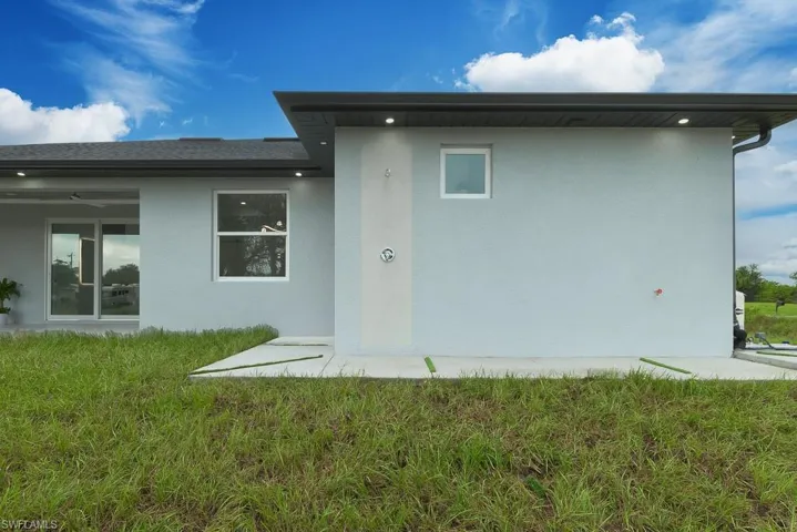 Back of property with ceiling fan and a yard