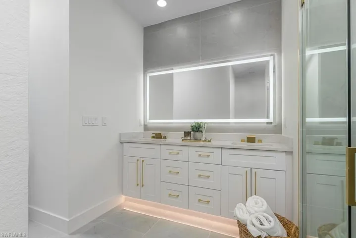 Bathroom featuring tile patterned floors, a shower with door, and vanity