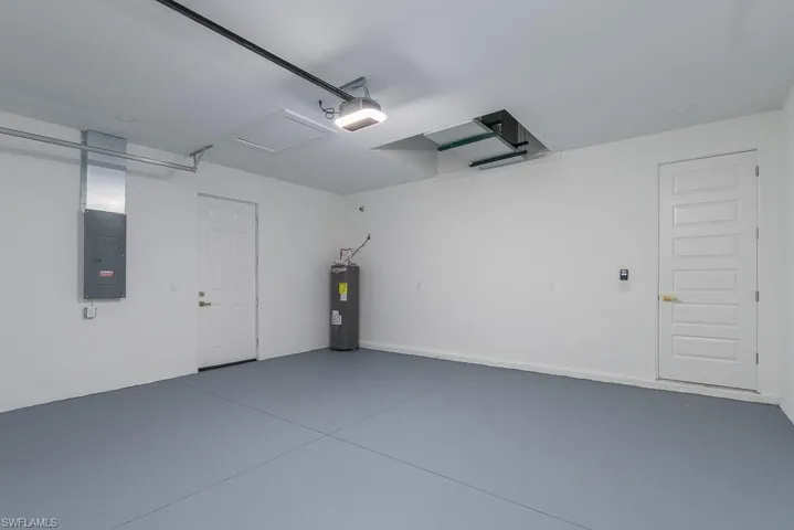 Garage with a garage door opener, water heater, and electric panel