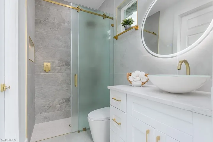 Bathroom with toilet, an enclosed shower, and vanity
