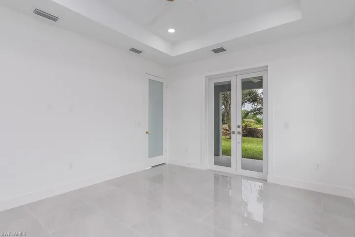 Unfurnished room featuring a tray ceiling, french doors, and ceiling fan