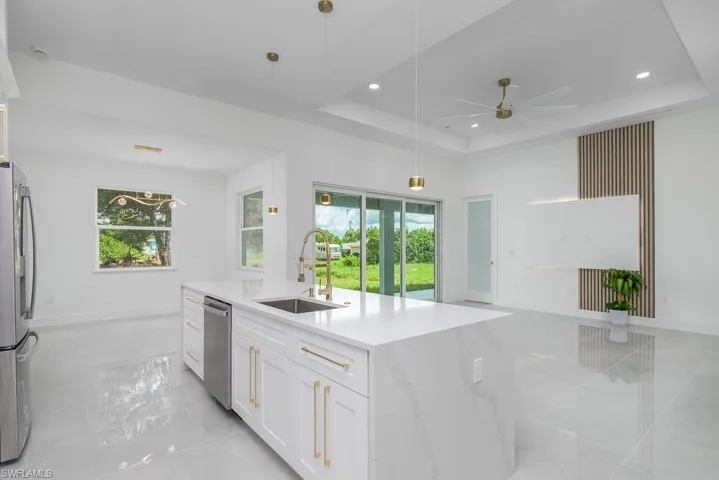 Kitchen featuring a raised ceiling, pendant lighting, sink, ceiling fan, and white cabinets