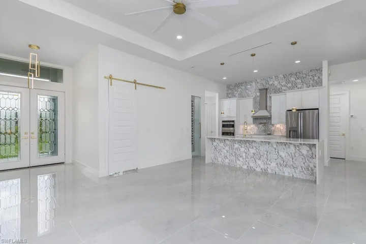 Kitchen featuring white cabinets, decorative light fixtures, stainless steel appliances, and a barn door