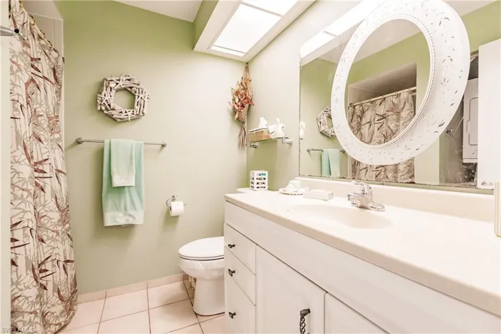 Bathroom featuring a skylight, toilet, tile floors, and large vanity