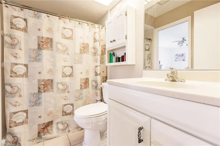Bathroom featuring tile flooring, large vanity, ceiling fan, and toilet