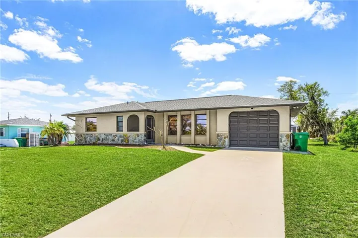 The property features a well-maintained lawn, a paved driveway, and a garage with a dark gray door